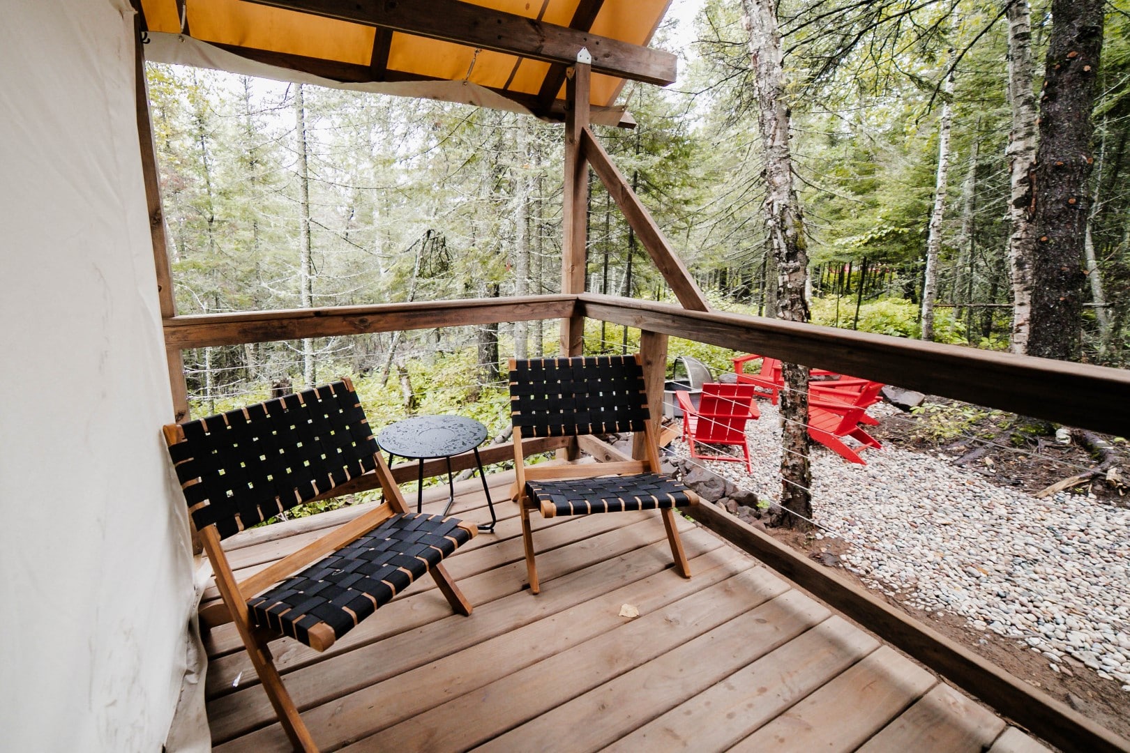 Secluded forest cabin deck with chairs and nature view.