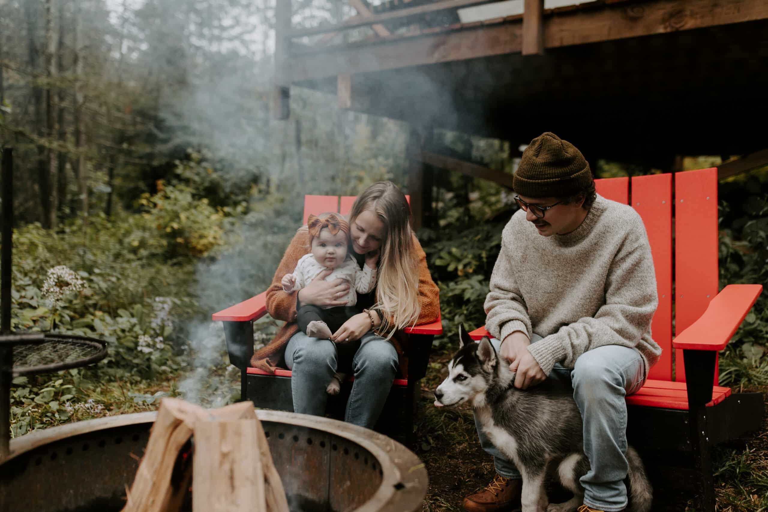 Family and dog by campfire in forest.