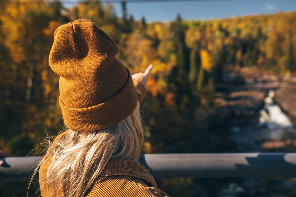 Person in beanie admiring autumn forest landscape