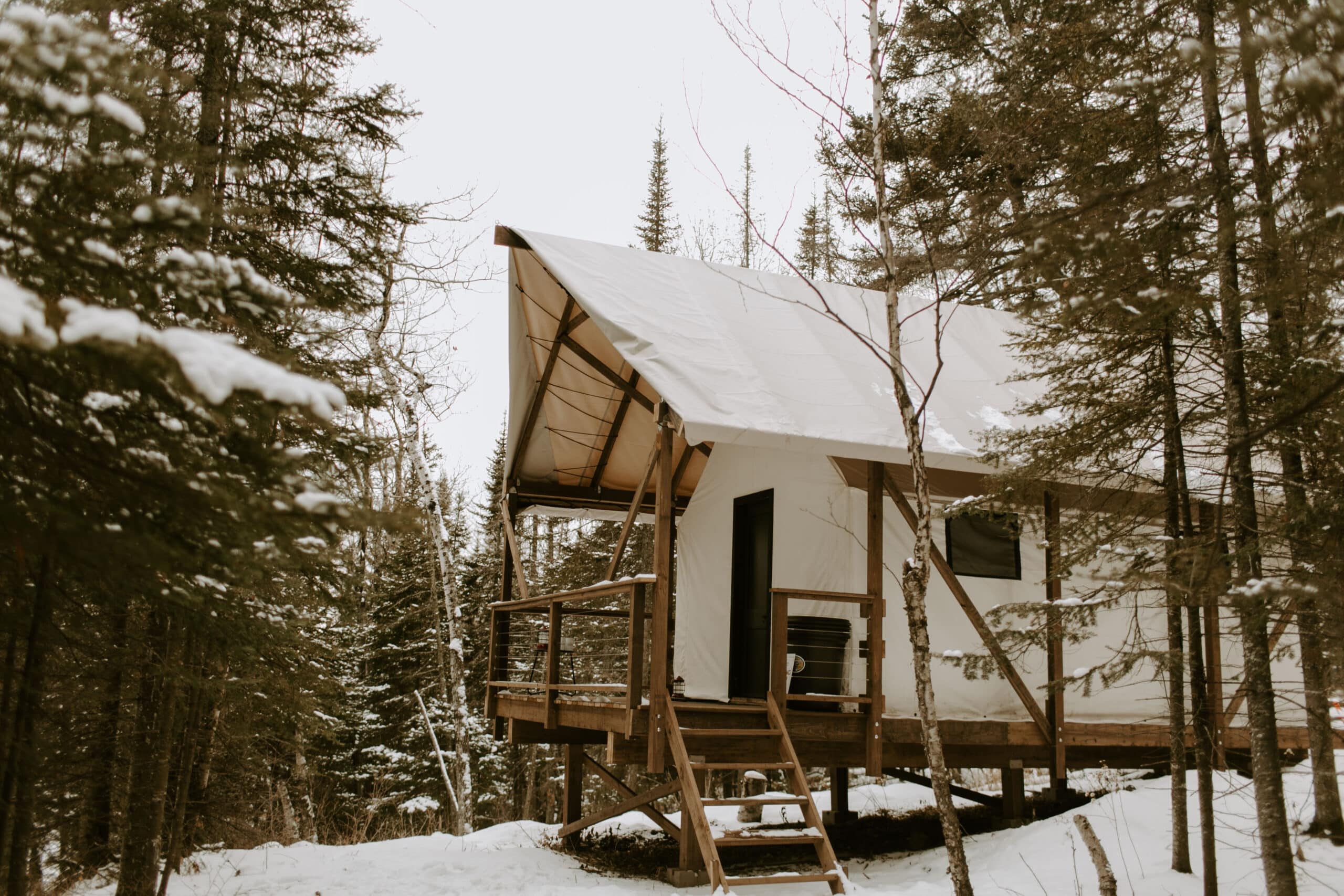 Cabin in snowy forest with wooden deck.