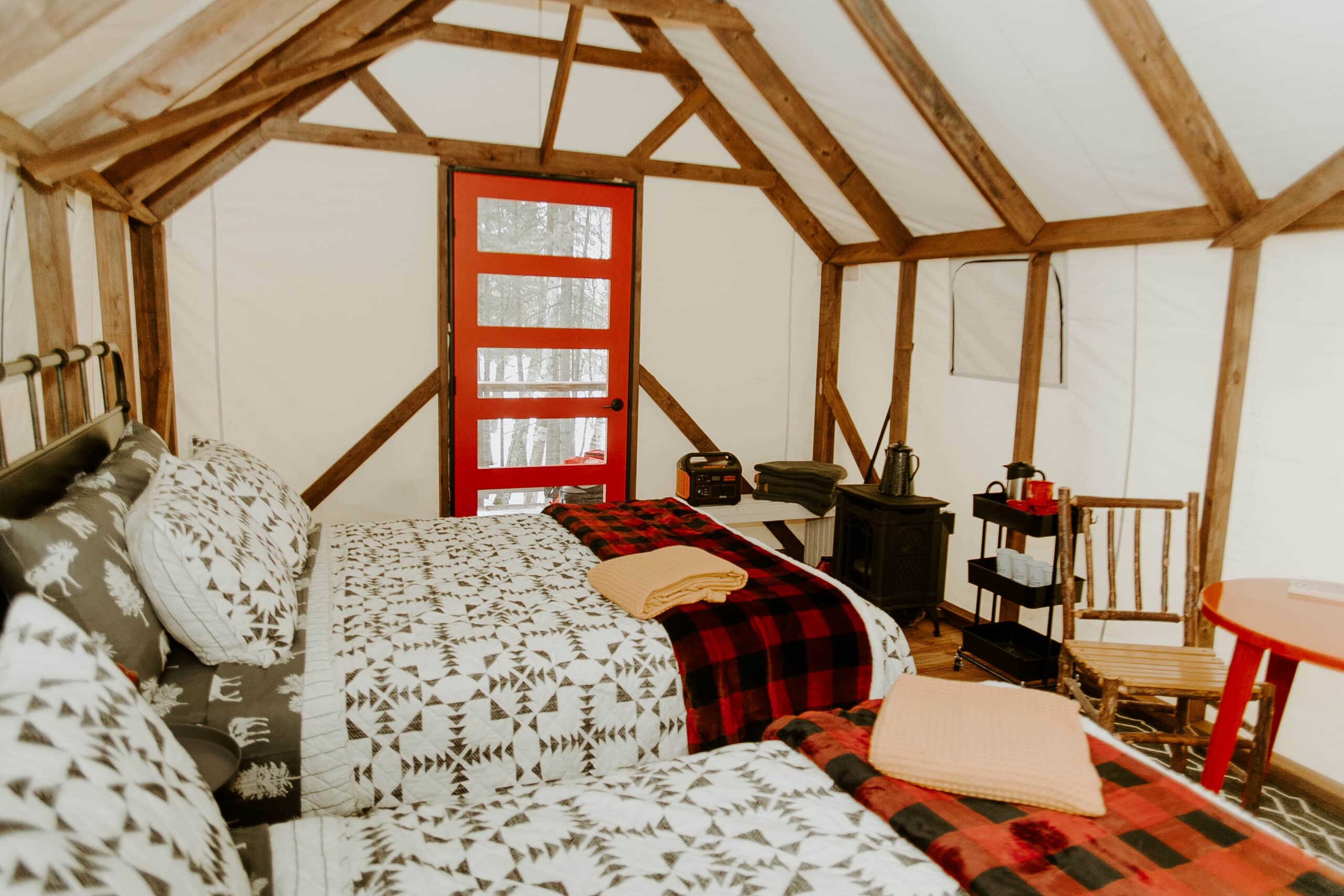 Cozy glamping interior with wood stove and comfy bed.