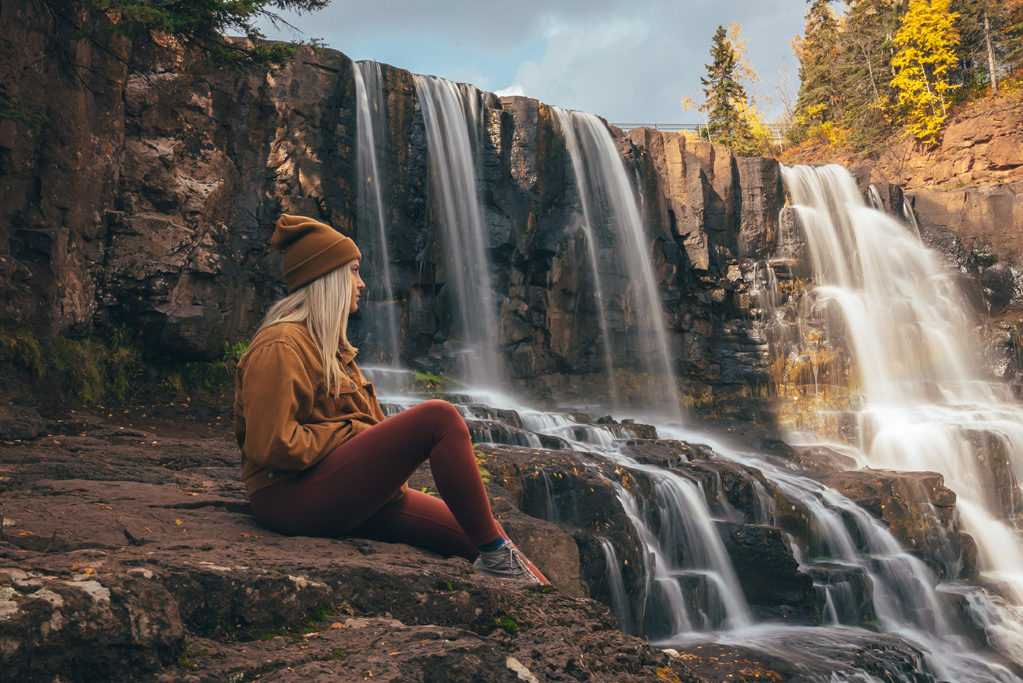 Woman sitting by a scenic waterfall