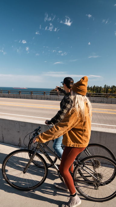 Couple biking near ocean on sunny day.