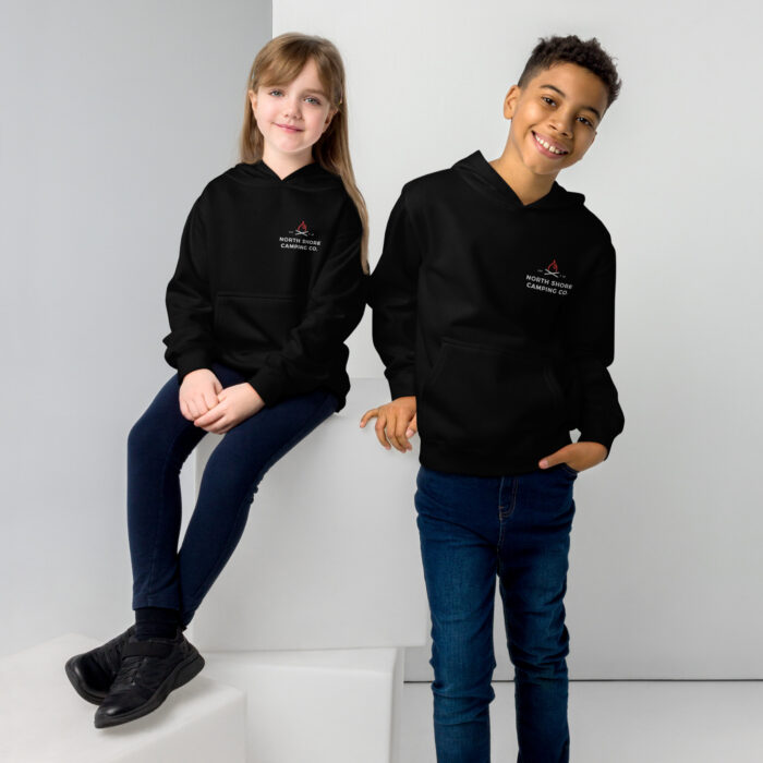 Kids wearing black hoodies and jeans smiling.