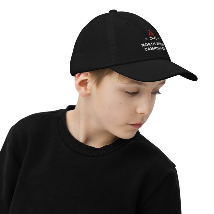 Child wearing black baseball cap and sweater.