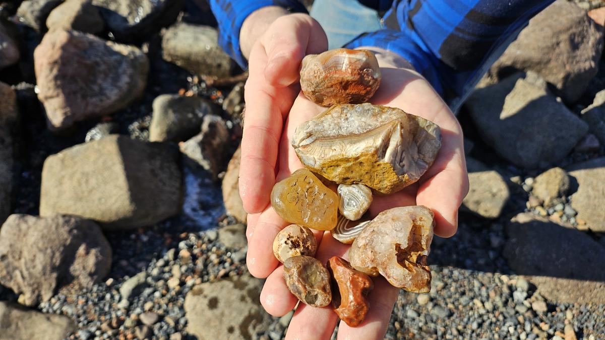 Hands holding colorful rocks on beach