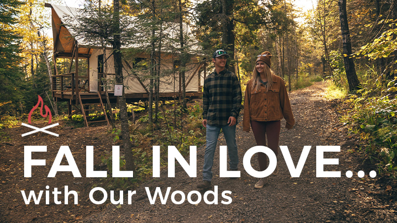 Couple walking in forest near cabin, autumn setting.