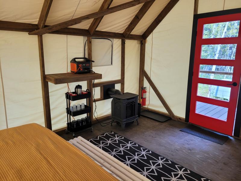Cozy cabin interior with stove and red door.