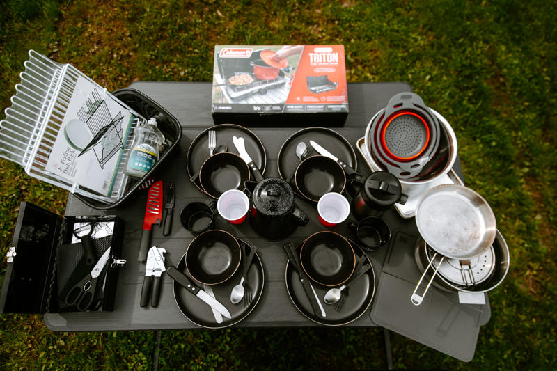 Camping cookware set arranged on outdoor table.