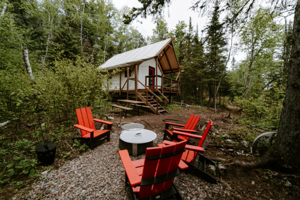 Forest cabin with red chairs and firepit