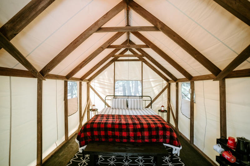 Cozy glamping tent interior with bed and rustic decor.