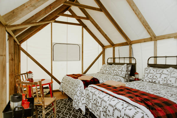 Cozy glamping tent with two beds and chairs.