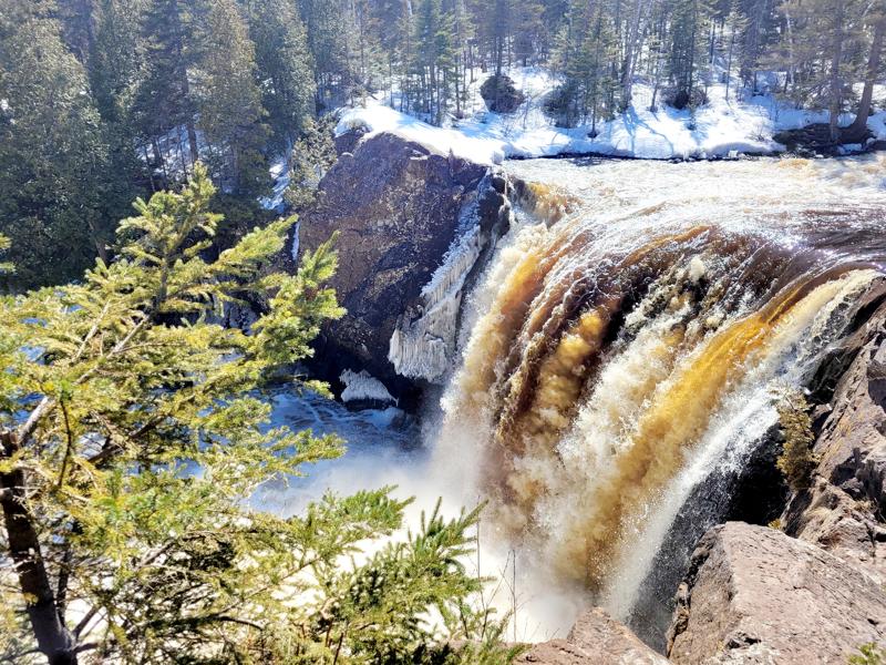 Waterfall cascading over snow-covered rocks in forest.