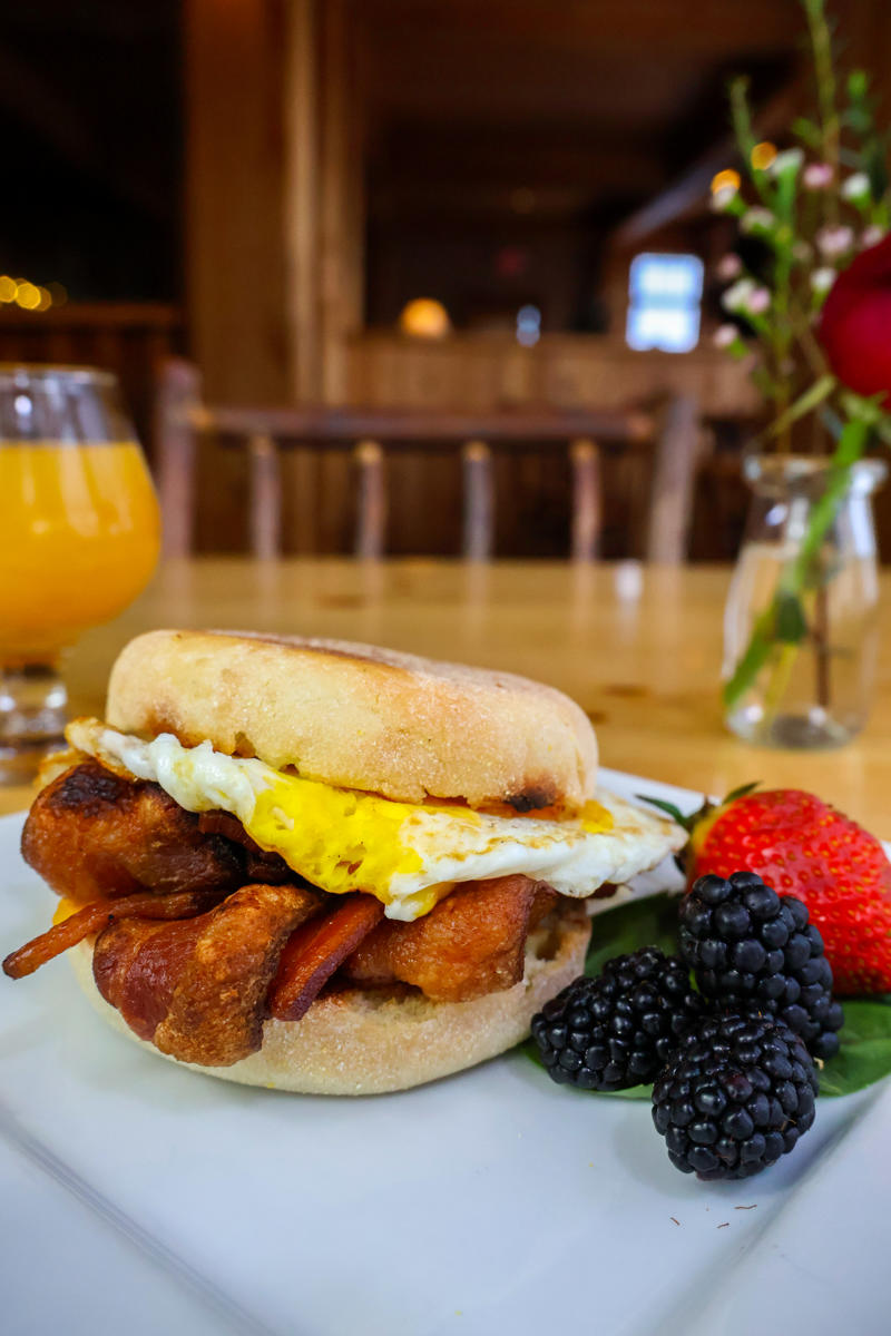 Breakfast sandwich with bacon, egg, and berries.