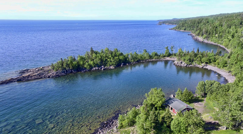 Aerial view of a forested lakeside cabin.