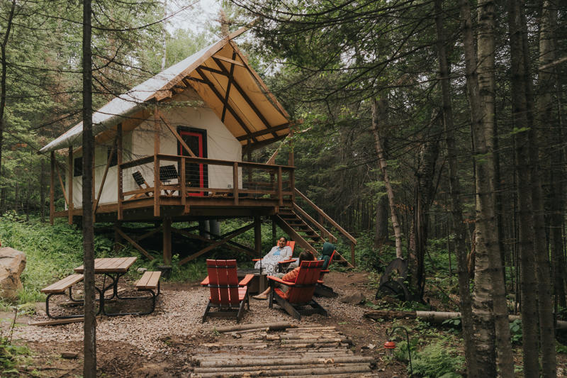 Forest cabin with outdoor seating area and fire pit.