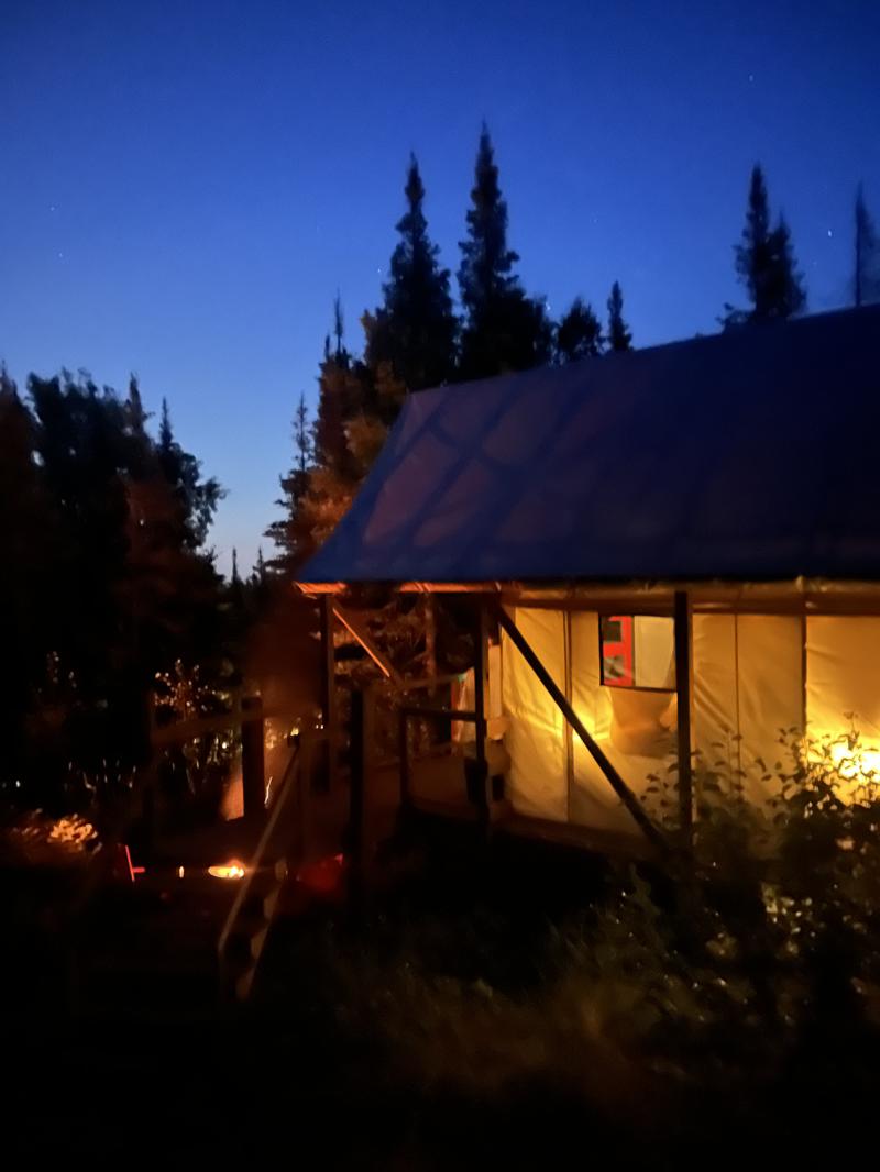 Glowing tent in forest at dusk