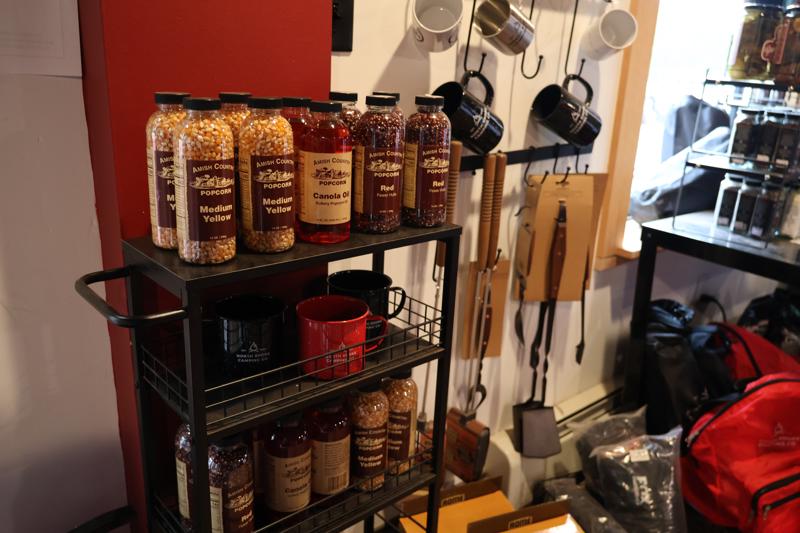Popcorn supplies and mugs on kitchen shelf display.
