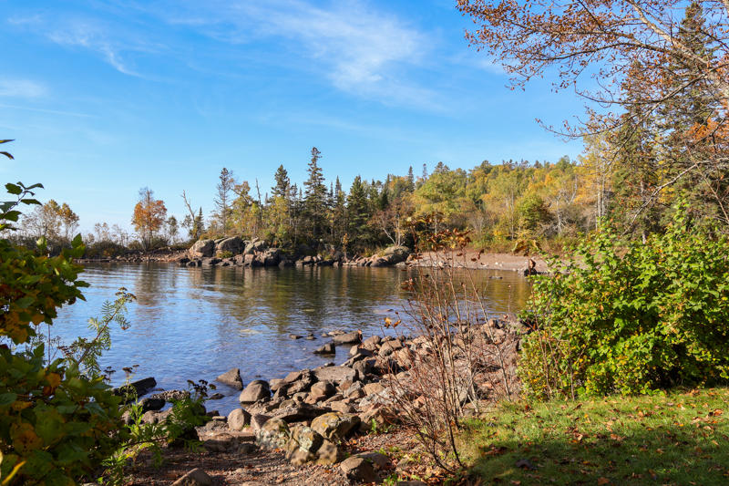 Scenic autumn lake with rocky shoreline and trees.