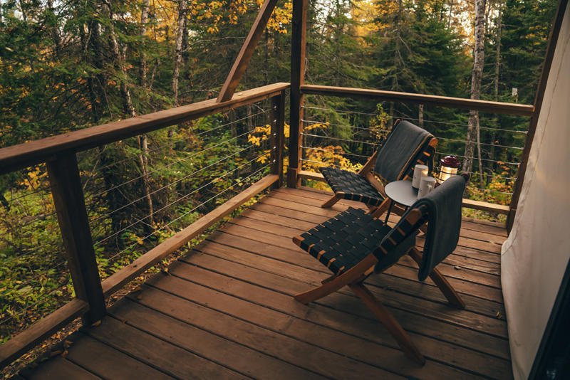 Cozy forest cabin deck with chairs and table.