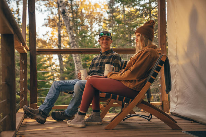 Couple enjoying coffee on a cozy wooden deck.