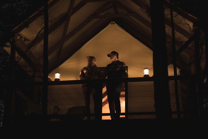 Couple standing on cabin porch at night.