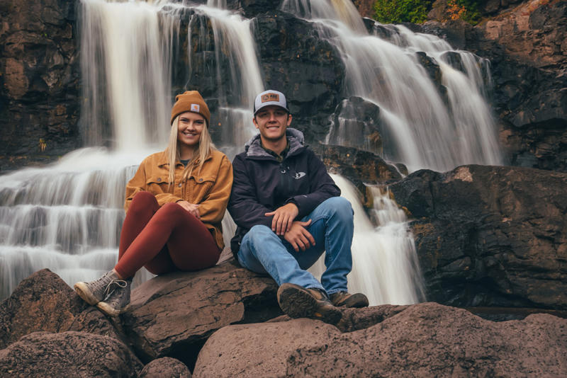 Couple sitting on rocks near waterfall