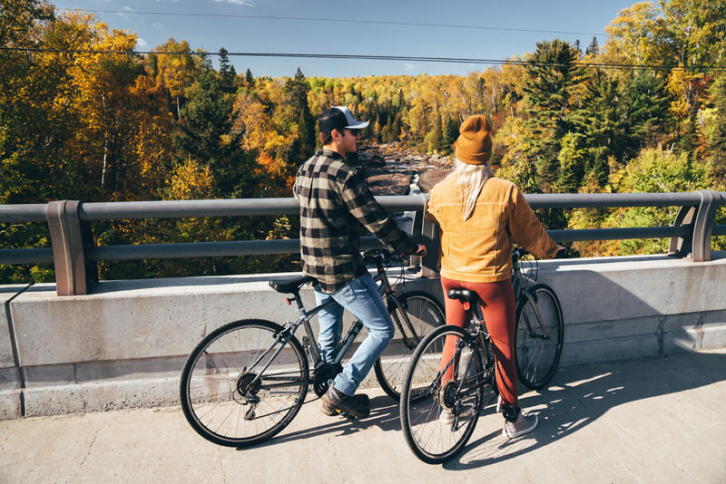 Couple on bikes admiring fall foliage view.