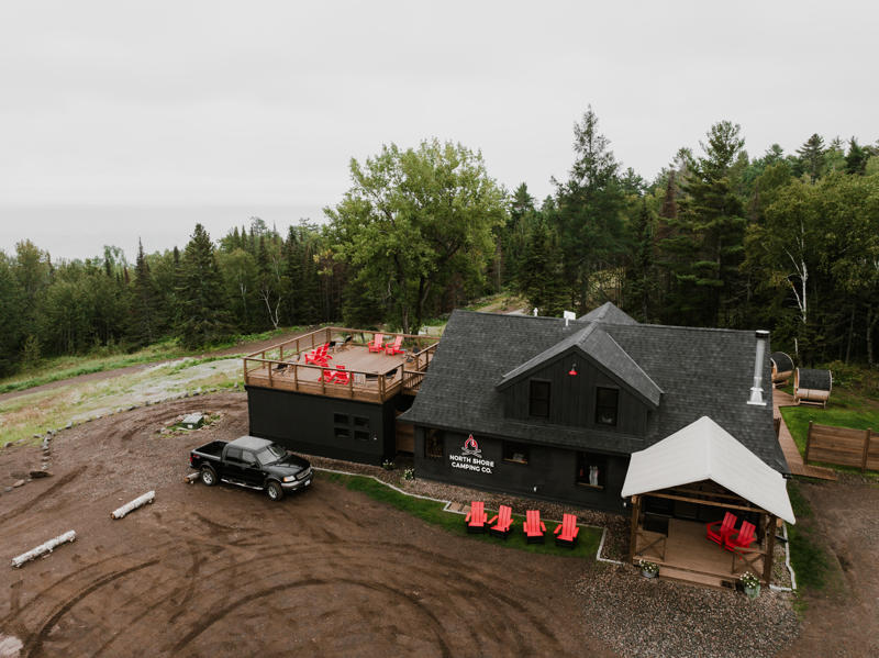 Wooded cabin with red chairs and parked truck.