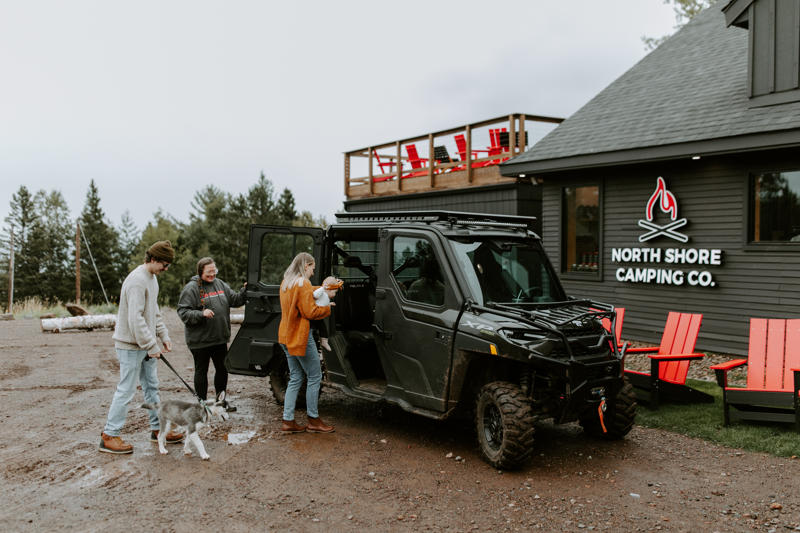 People with dog near camping vehicle.