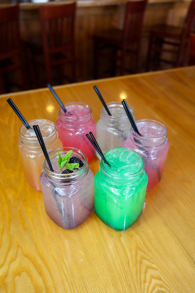 cove crossings food bev feb 2026 70 Colorful drinks in jars on wooden table.