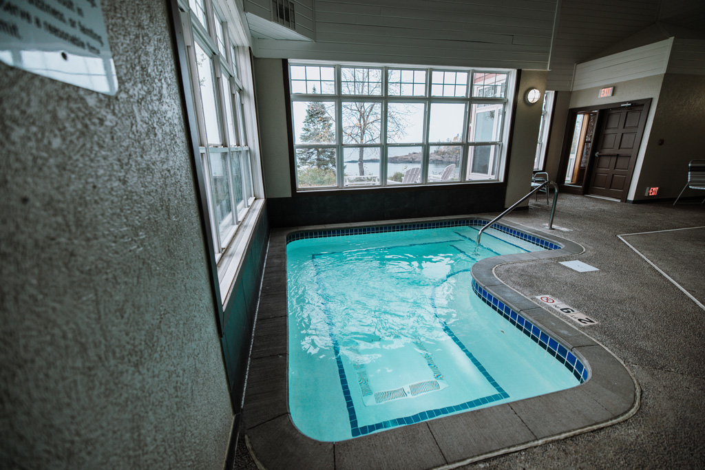covepointlodge fall2022 images 384 Indoor hotel pool with large windows, scenic view.
