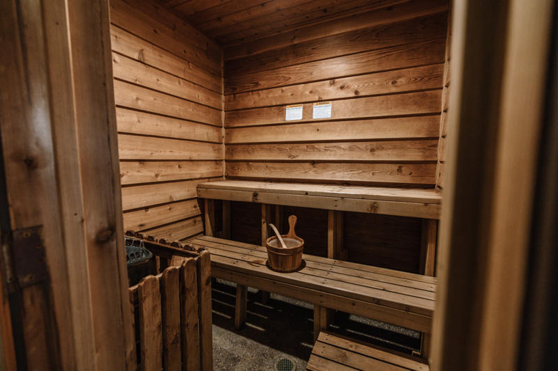 covepointlodge fall2022 images 391 Wooden sauna interior with benches and bucket.