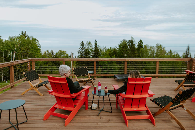 Two people relaxing on deck with forest view.