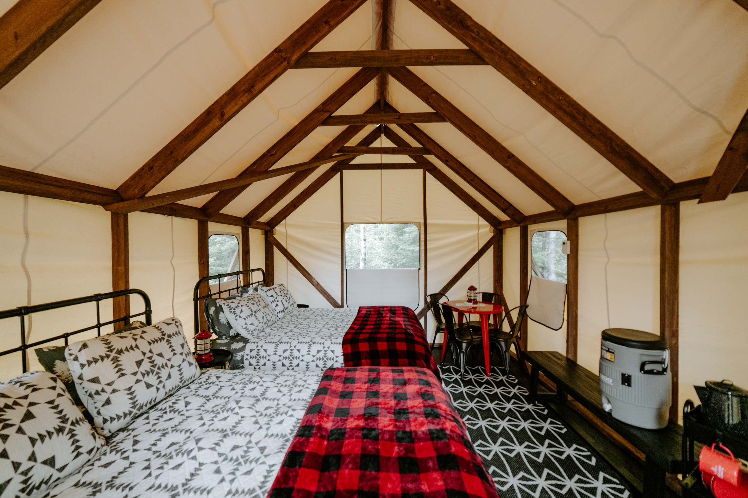 Glamping tent interior with double beds and chairs.