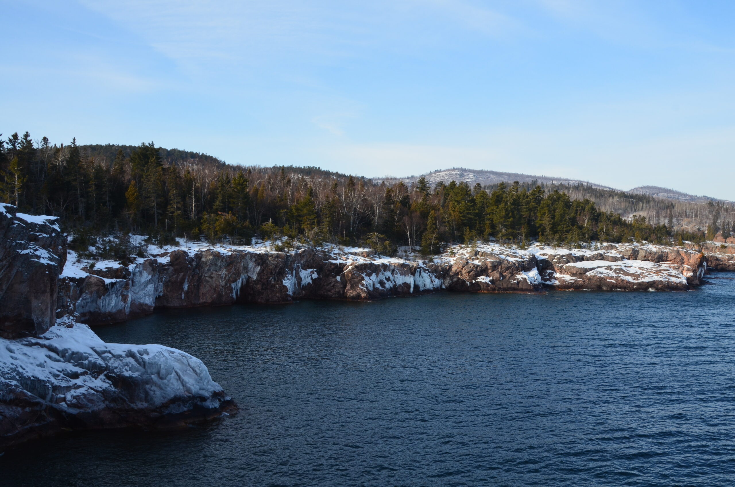 dsc 0003 Snowy rocky shoreline with evergreens by lake.