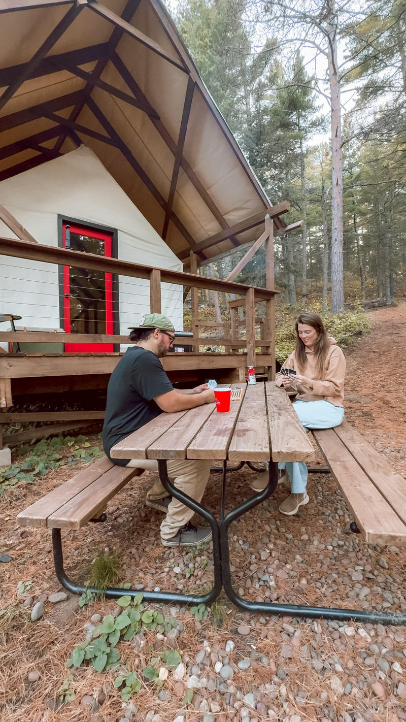 People playing cards at picnic table outside cabin