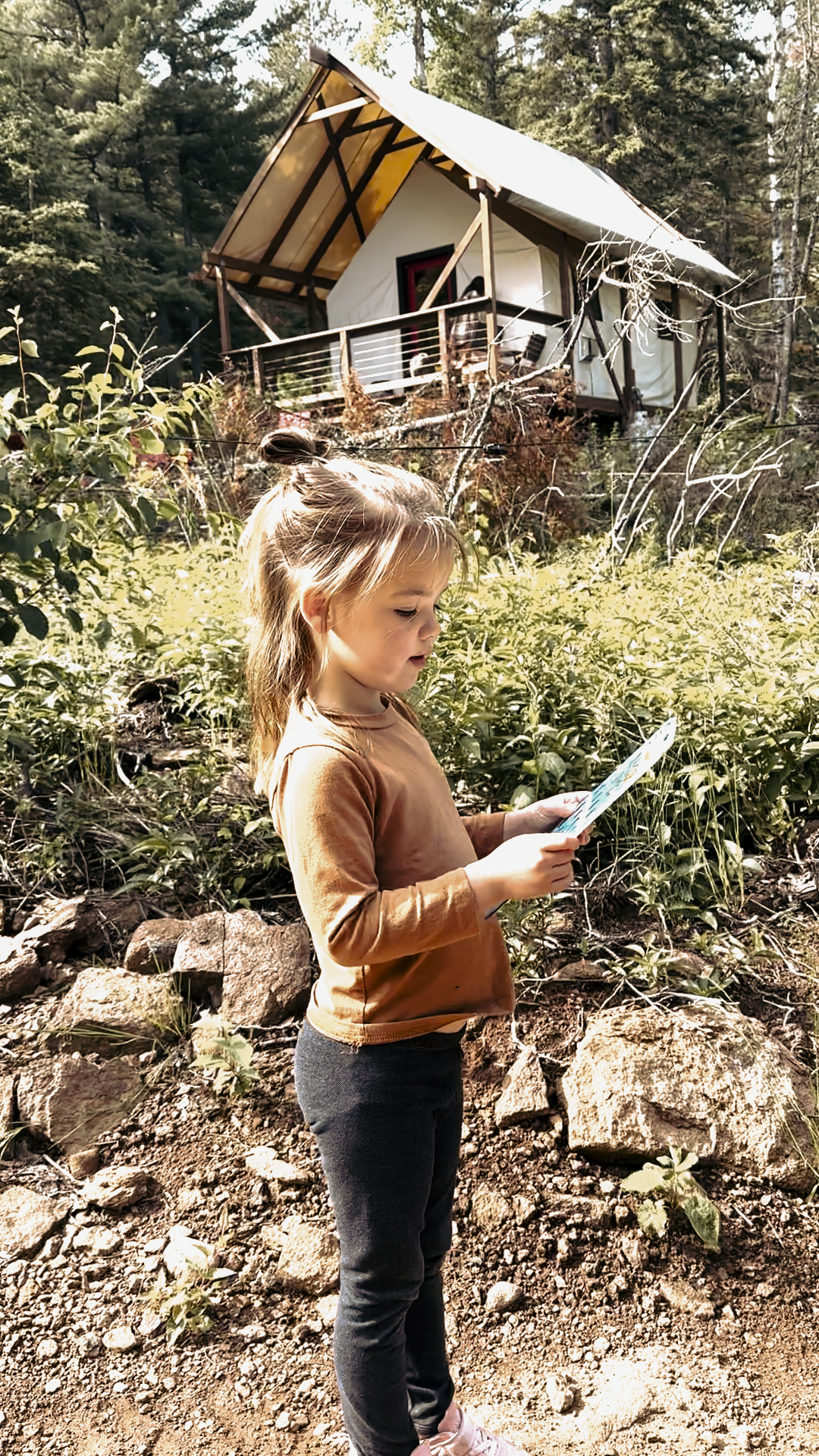 girlscavengerhunt (1) Girl reading in front of cabin in woods.