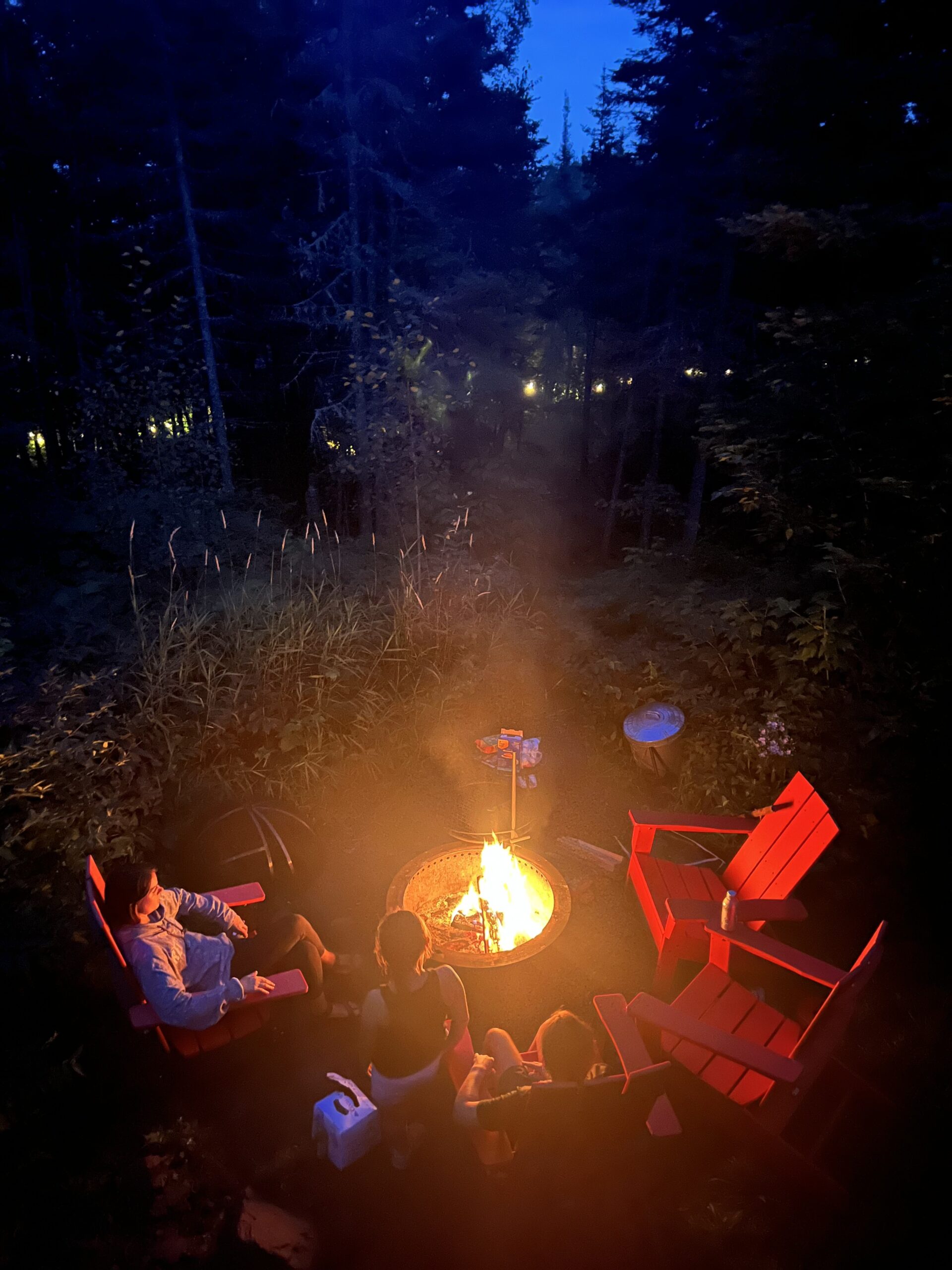 img 1017 People enjoying campfire with red chairs in forest.