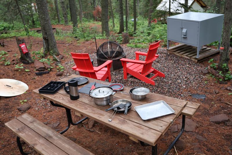Outdoor campsite with picnic table and kitchenware.