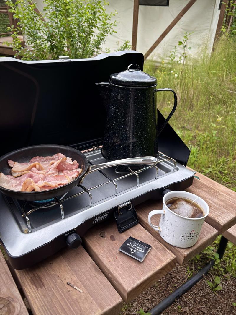 Camping breakfast with bacon and coffee on stove