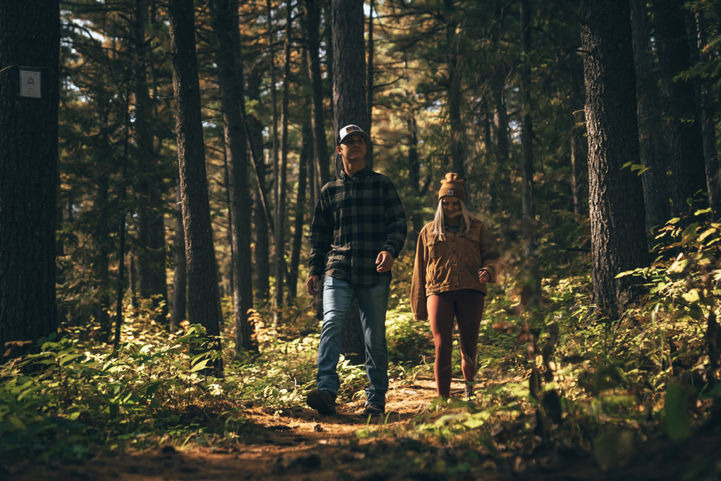 Couple hiking through a dense forest trail.
