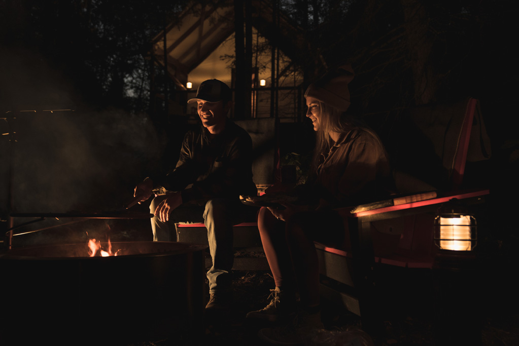 Couple sitting by campfire at night.