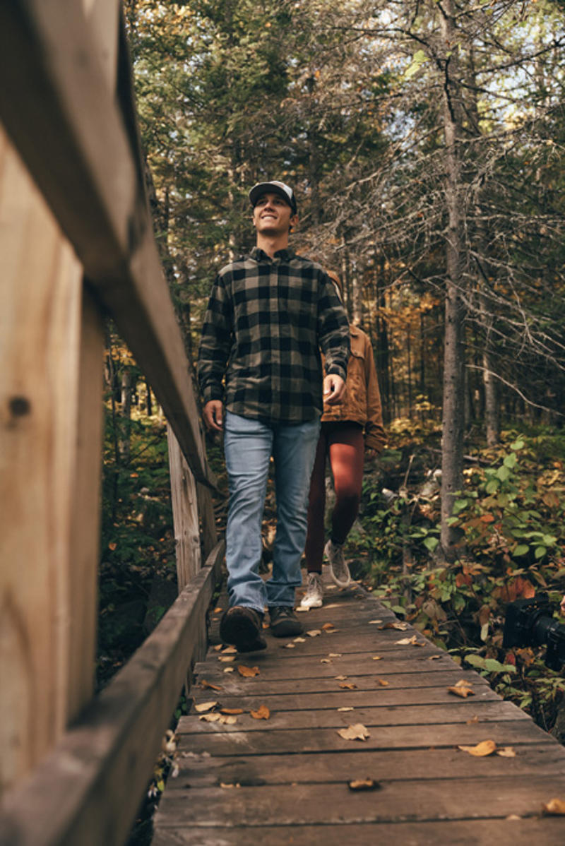 northshorecampingco fall2022 images 3 People hiking on forest boardwalk bridge.