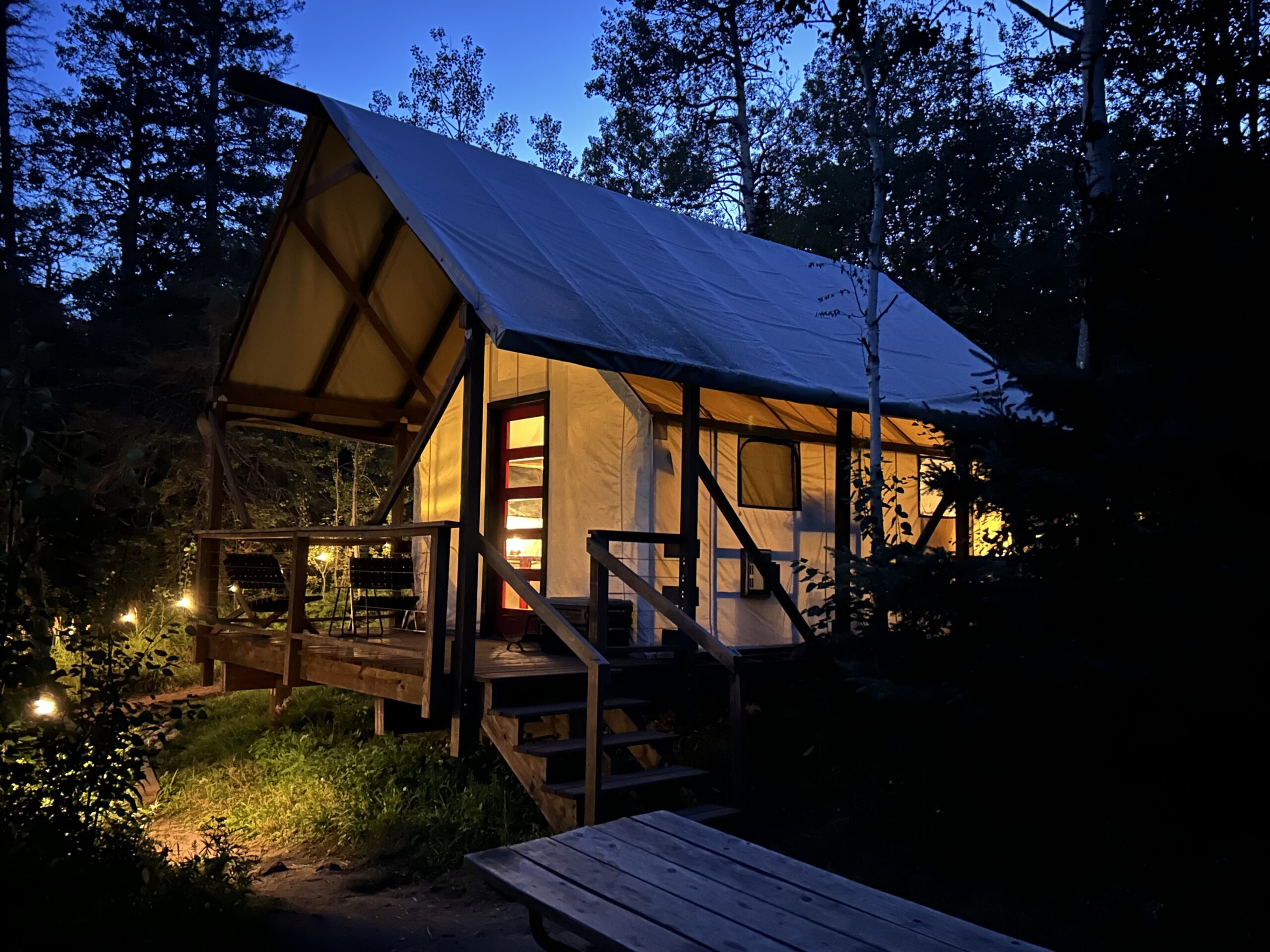 Glowing cabin in forested campsite at dusk.