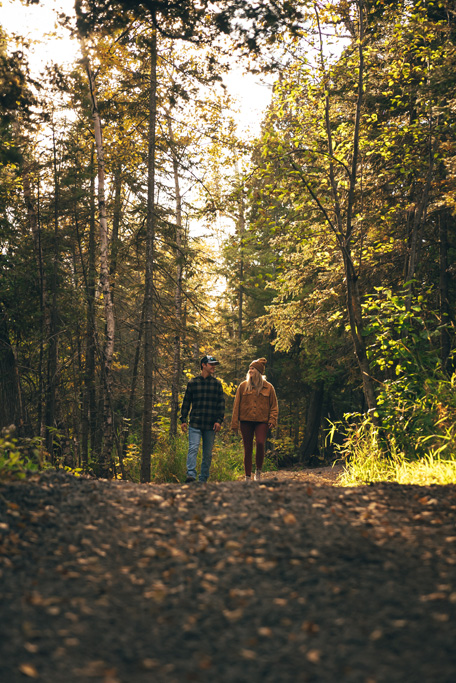 northshorecampingco fall2022 images 147 Couple walking along sunlit forest trail