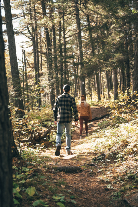 northshorecampingco fall2022 images 22 Two people hiking on a forest trail