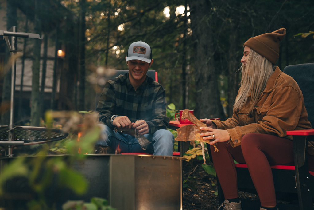 northshorecampingco fall2022 images 220 Couple sitting by campfire in forest campsite