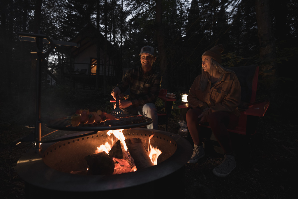 northshorecampingco fall2022 images 230 Couple roasting food by campfire at night
