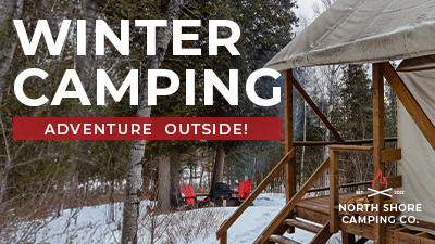 Snowy winter campsite beside a canvas tent